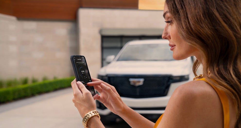 lady checking her mobile with a Cadillac vehicle background | Sheboygan Cadillac in Sheboygan WI